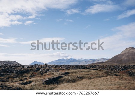Travel to Iceland. beautiful mountain landscape in Iceland. Icelandic landscape with snowy peak mountains, blue sky and yellow autumn grass on the foreground.