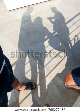 Silhouettes on the floor tiles of men and women who are talking.