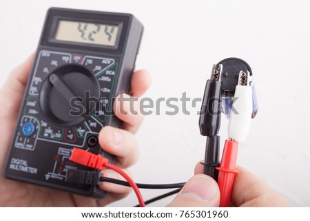 Digital electric tester multimeter in hands on white background.

