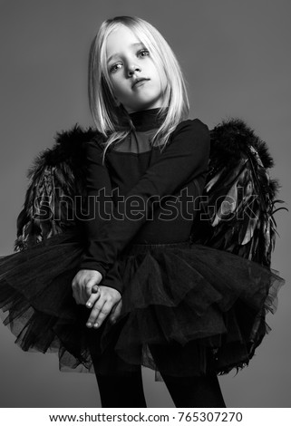 baby angel in black on a monophonic studio background with wings
