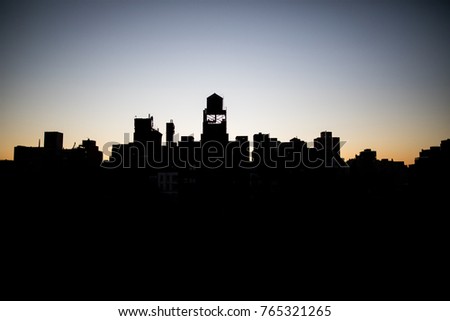 Silhouette of New York City skyline at sun rise featuring raised water tank