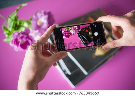 man photographs on smartphone magazines and flowers