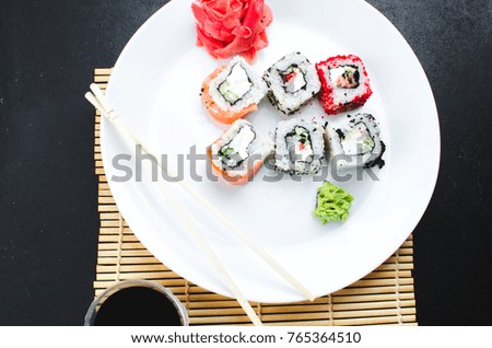 on the plate is white, lined with different rolls, sushi, Red, black, Philadelphia sesame