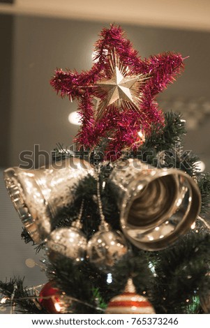 Christmas Silver bell and star hanging on a beautiful Chrismas tree surrounded by red and white shinning ball