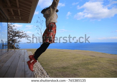 Jumping girl in a sunny hill ,open sky and ocean , Atami, Izu, Japan.