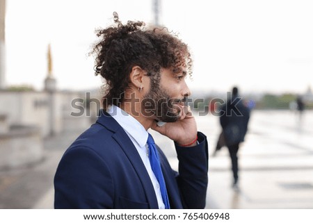Attractive businessperson calling cooperator and disputing by phone with Eiffel Tower in background in. Young man making official journey to France. Concept of works debating and detached duty to