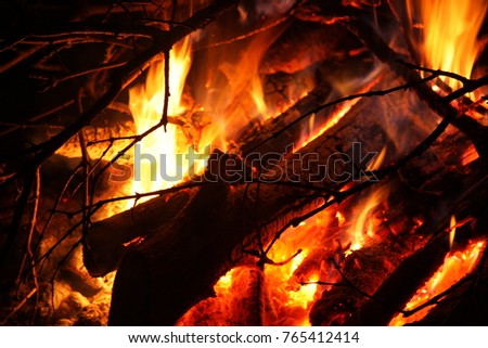 Firewood and branches burn in the fire. Fireplace, fire, heat from the fire. Orange flames.