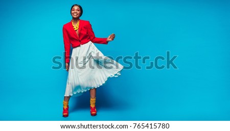 Full length shot of attractive woman in beautiful dress. African female fashion model standing over blue background with copy space. Royalty-Free Stock Photo #765415780