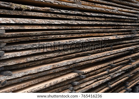 Folded wooden brown and gray planks in a sawmill. Piled alder boards as texture.
