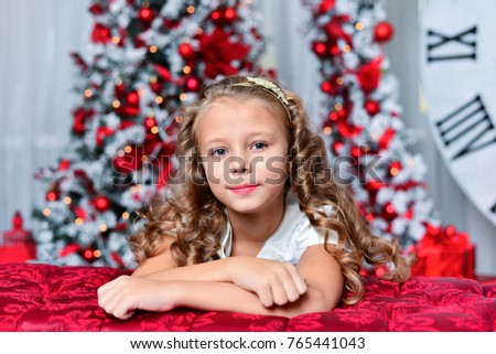 little girl in white dress with Christmas gift sitting near Christmas tree, a nice smile