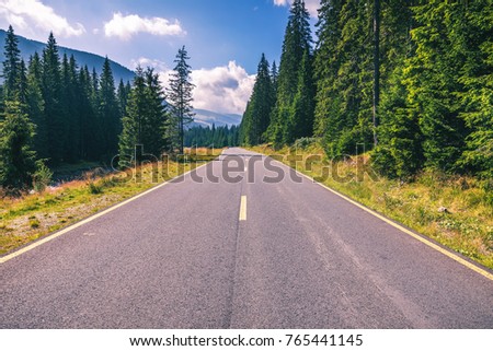 Mountain road. Landscape with rocks, sunny sky with clouds and beautiful asphalt road in the evening in summer. Vintage toning. Travel background. Highway in mountains. Transportation Royalty-Free Stock Photo #765441145