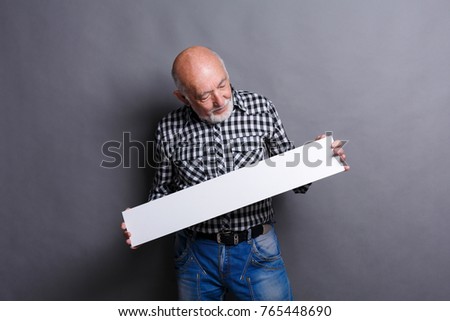 Senior man with blank white board. Mature male looking at advertising sheet, copy space