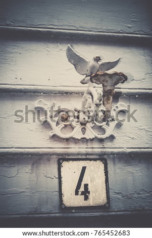 Retro white door number four plaque on a wall of a wooden house