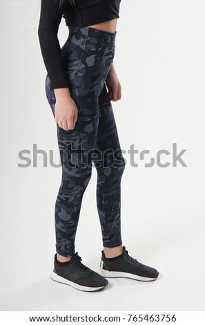 Girl in camouflage leggings, black blouse and black sneakers