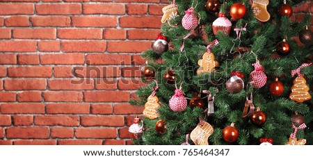 Wide horizontal picture of a christmas tree decorated with ginger cookies on brick wall background