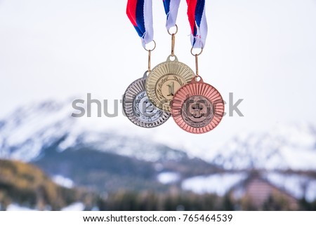 Gold silver and bronze medal with winter mountains in background. Sport trophy photo