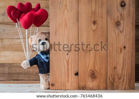 A photo of teddy bear holding heart-shaped balloon with wood board texture