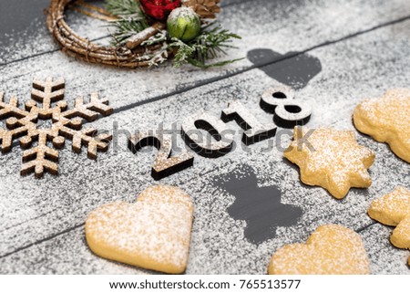 2018 numbers and christmas different shaped cookies with sugar powder and wooden snowflake on wooden table. Top view