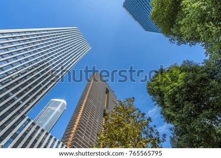Bottom view of modern skyscrapers in business district against blue sky
