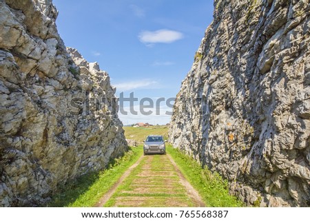 The car moves along the road carved into the rock
