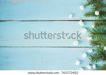 Christmas border with branch of fir tree and marshmallows on wooden background. Top view copy space