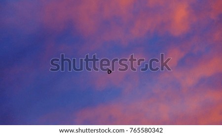 Silhouette sunset with vivid sky at dusk and clouds abstract background with a small heart balloon in the sky