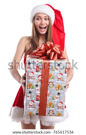 Happy girl in Christmas costume, is holding a gift box and is looking downwards . Isolated on white background.