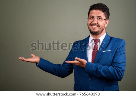 Studio shot of bearded Persian businessman wearing suit against colored background