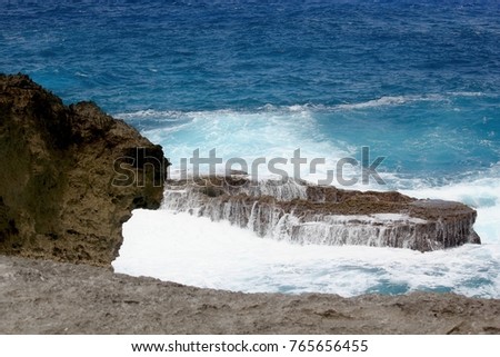 Foaming waves roll around a jutting coral in the ocean at the At Matmos Fishing Cliff on Rota, a destination in the Northern Mariana Islands.