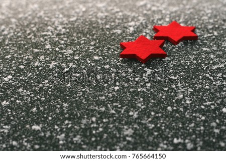 two red felt stars lying on asphalt with snowflakes