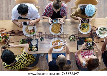Top view of happy people taking photo of food on mobile phone before gathering for eating food, enjoying the party and communicate with family and friends at table on holiday, soft focus background