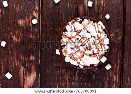 Hot chocolate with marshmallow in brown cup on wooden background. Copy space