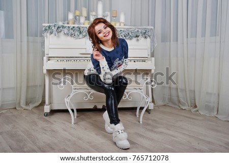 Girl wear warm sweater background piano with candles on studio. Happy new year winter holidays concept.