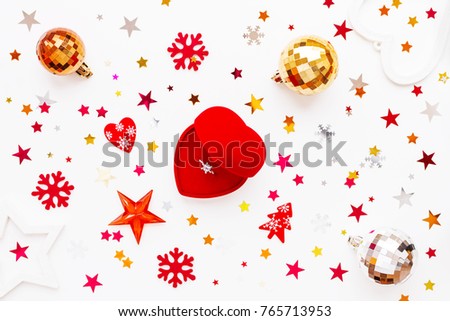Christmas and New Year holiday background with decorations and engagement ring with diamond in gift heart box. Shiny balls, felt snowflakes and star confetti. Flat lay, top view.