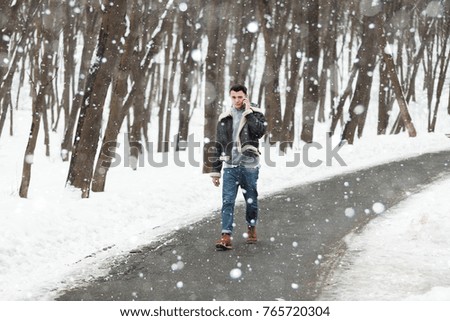 a young guy holding a phone. winter background
