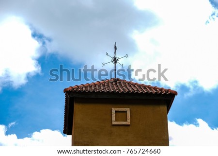 A building has compass on the top with blue sky and white cloudy