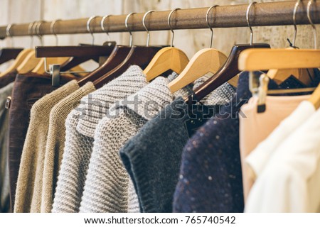 Fashion trend concept. Warm winter ladies clothes collection with knitted wool jumpers on wooden hangers. Royalty-Free Stock Photo #765740542