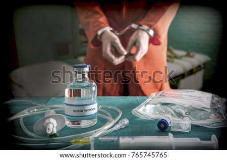 Prisoner handcuffed to death by lethal injection, vial with sodium thiopental and syringe on top of a table, conceptual image Royalty-Free Stock Photo #765745765