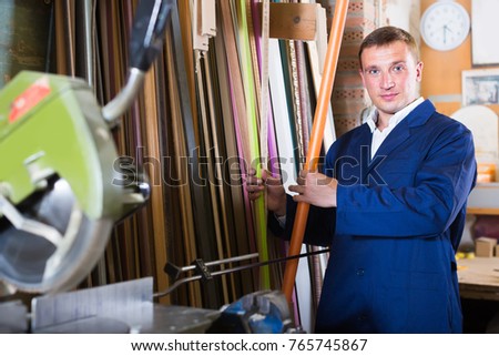 professional male seller standing in picture framing studio with wooden details
