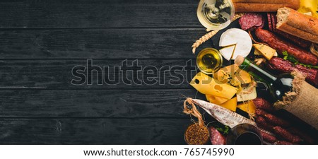 A bottle of wine, cheeses and traditional sausages on a wooden background. Brie cheese, blue cheese, gorgonzola, fuete, salami. Free space for text. Top view.