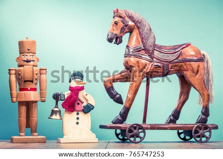 Retro antique Christmas wooden horse on wheels toy, old snowman with jingle bell and nutcracker. Holiday greeting card concept. Vintage instagram style filtered photo