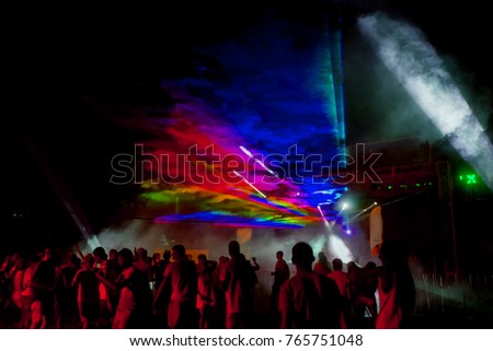 Laser show. Luminous performance at nightclub party. Creative Light show, silhouettes of crowd on dance floor. light picture in smoke of smoke machine. Stylized  film, grain, distortion, motion blur