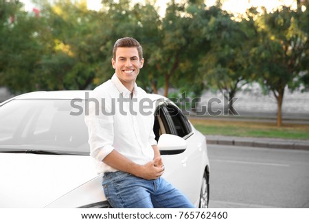 Young man standing near car on city street