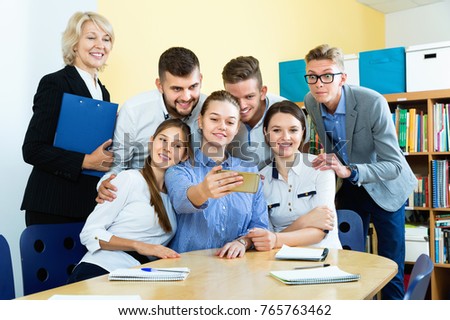 Cheerful positive  students with female teacher making selfie indoors