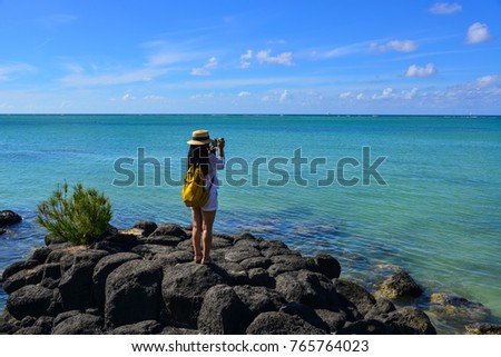 A woman standing and taking pictures in Cap Malheureux, Mauritius.
