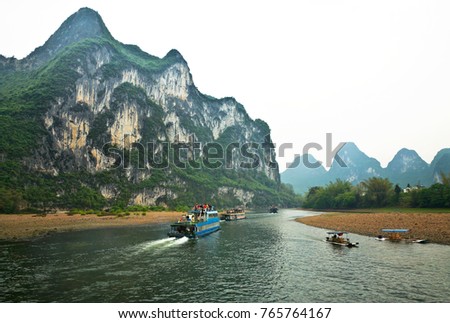 China. Li River (Lijiang River). Numerous tourists take pictures of the natural landmark of Fresco Hill from the pleasure boats sailing from Guilin to Yangshuo on a foggy day