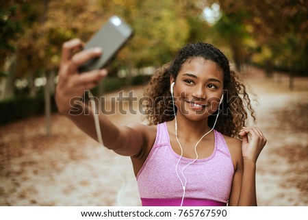 Young sporty woman close up portrait taking selfie in a park.