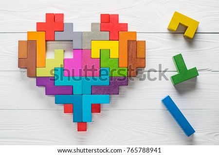 Heart made of colorful wooden shapes, top view, flat lay. Health background concept. Logical tasks. Conundrum, find the missing piece of the proposed.