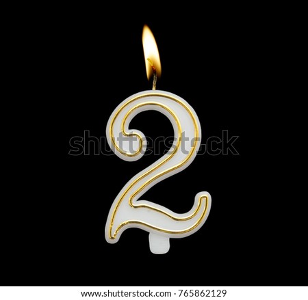 Burning birthday candle isolated on black background, number 2
