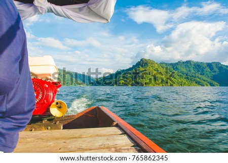 Wooden Thai traditional long-tail boat on a lake with mountains and rain forest in the background,copy space.
